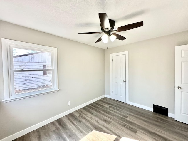 unfurnished bedroom featuring ceiling fan, wood finished floors, baseboards, and a textured ceiling