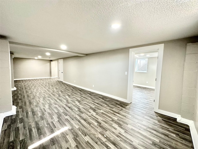 finished below grade area featuring wood finished floors, baseboards, and a textured ceiling