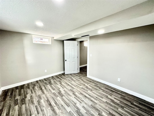 below grade area featuring wood finished floors, baseboards, and a textured ceiling