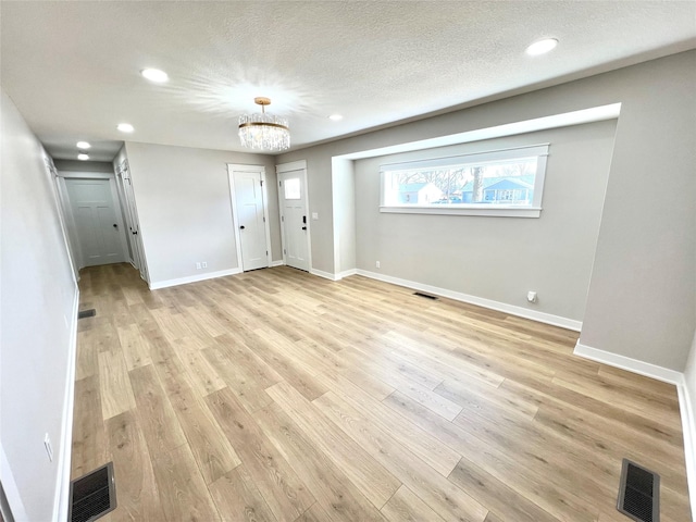 unfurnished living room featuring visible vents, light wood-type flooring, and baseboards