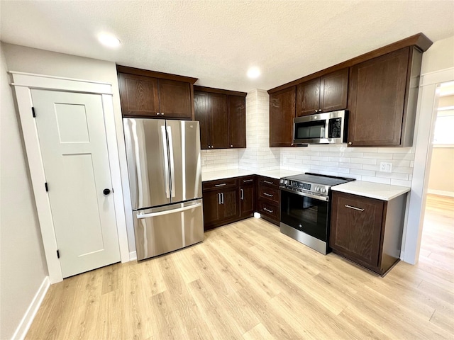 kitchen featuring light wood-type flooring, dark brown cabinetry, and appliances with stainless steel finishes