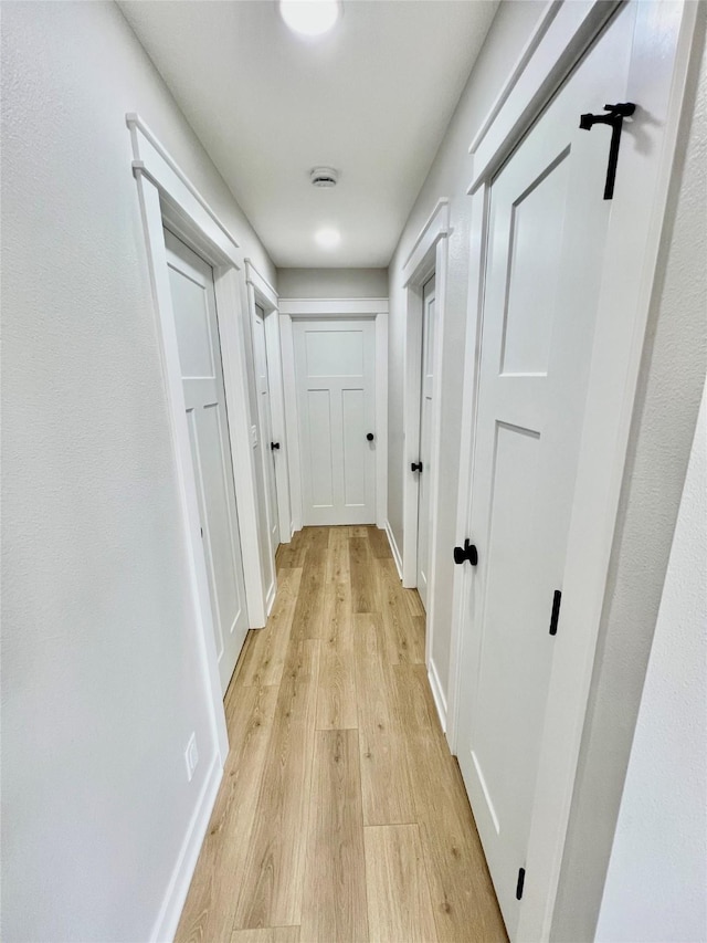 corridor featuring light wood-type flooring and baseboards