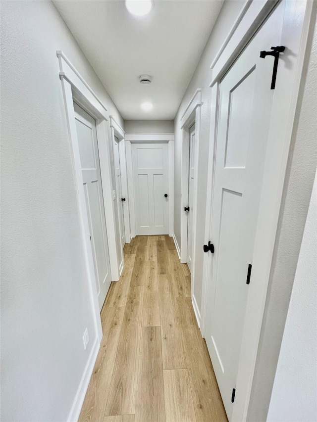 corridor with light wood finished floors and baseboards