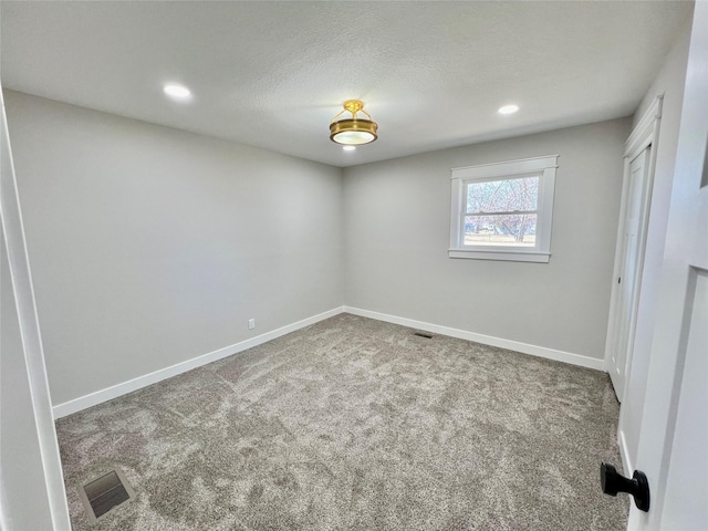 empty room featuring a textured ceiling, carpet, baseboards, visible vents, and recessed lighting