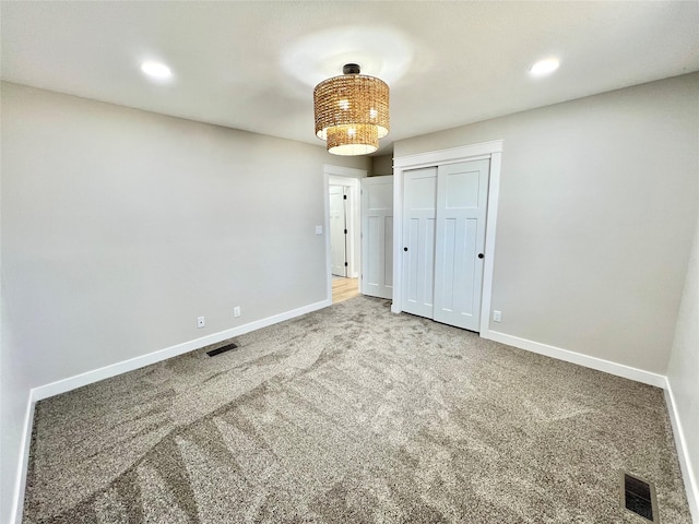 unfurnished bedroom featuring baseboards, carpet floors, visible vents, and a closet