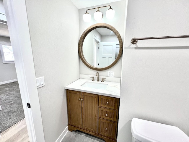 bathroom featuring toilet, vanity, and baseboards