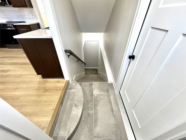 stairway with wood finished floors and baseboards