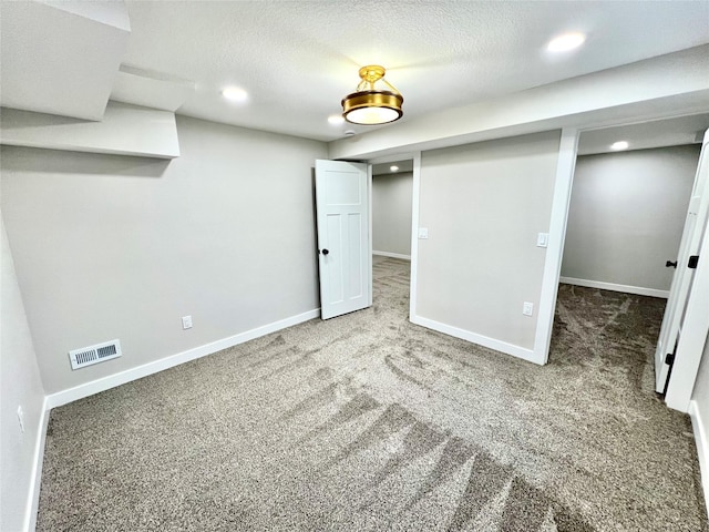 finished basement with baseboards, visible vents, recessed lighting, a textured ceiling, and carpet flooring