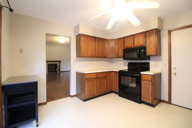 kitchen featuring light countertops, brown cabinets, a glass covered fireplace, black appliances, and a ceiling fan