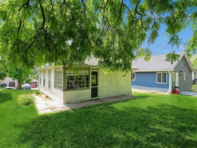 back of house featuring a yard and stucco siding