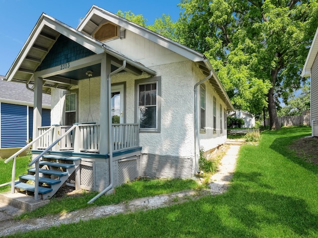 view of front of home with stucco siding, a porch, and a front lawn