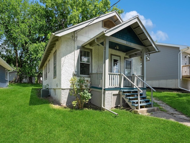 view of front of property with covered porch, central AC, and a front yard