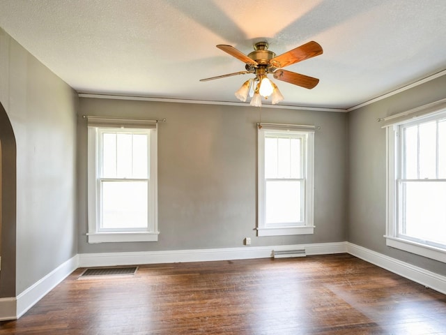 spare room featuring visible vents, arched walkways, baseboards, and dark wood-style floors