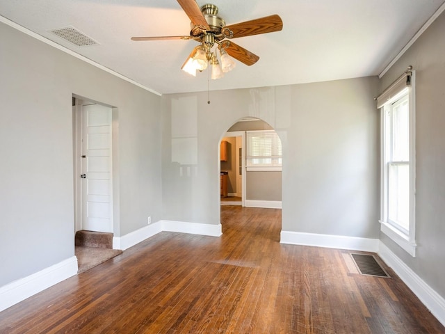 spare room featuring wood finished floors, arched walkways, visible vents, and ceiling fan