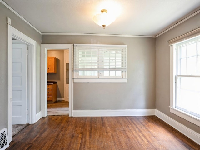 spare room with a wealth of natural light, crown molding, baseboards, and dark wood-style flooring