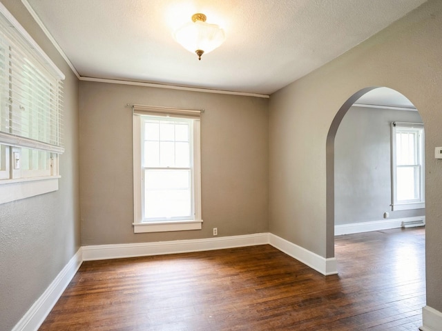 unfurnished room featuring baseboards, arched walkways, wood-type flooring, a textured ceiling, and crown molding