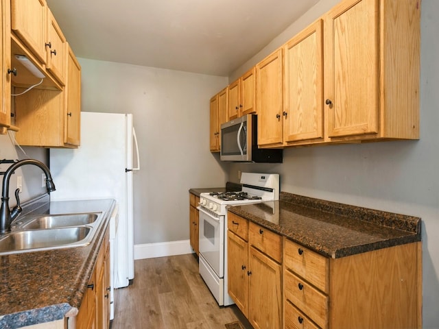 kitchen featuring wood finished floors, baseboards, gas range gas stove, a sink, and stainless steel microwave