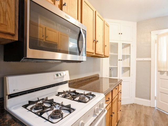 kitchen with stainless steel microwave, light wood-style floors, and gas range gas stove