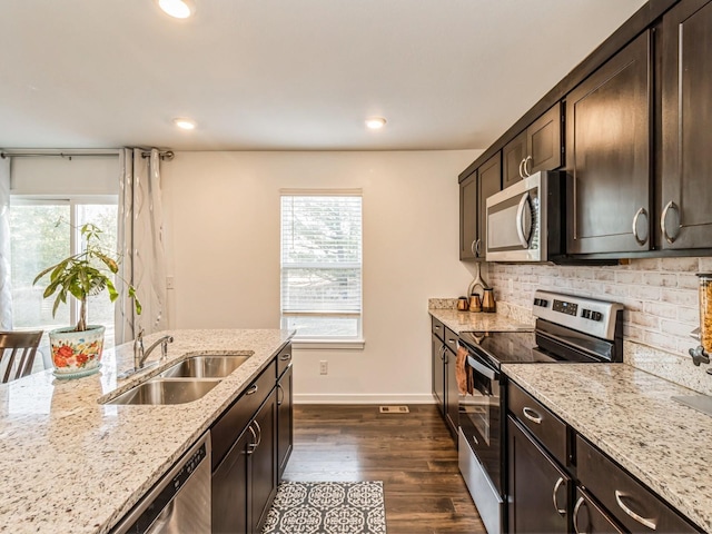 kitchen featuring dark wood-style floors, a sink, dark brown cabinetry, appliances with stainless steel finishes, and backsplash