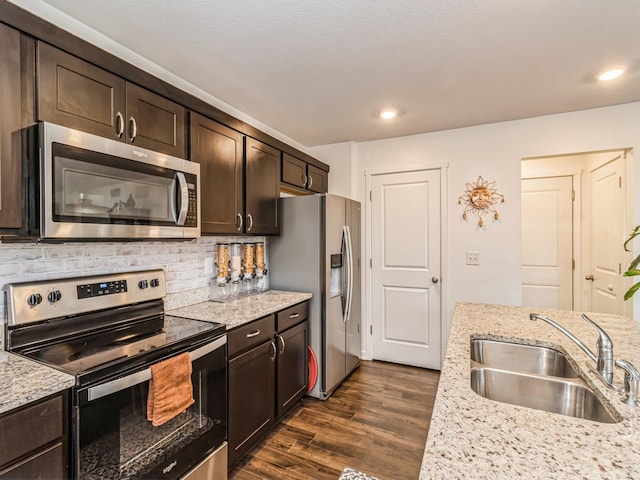 kitchen featuring a sink, stainless steel appliances, decorative backsplash, dark brown cabinets, and dark wood-style flooring