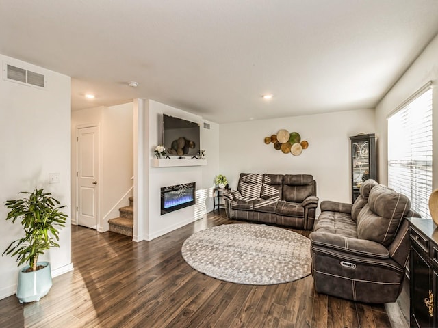 living room with visible vents, a glass covered fireplace, wood finished floors, baseboards, and stairs