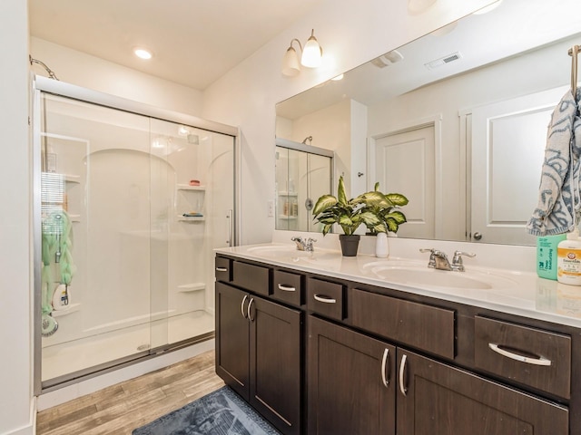 bathroom with a sink, wood finished floors, and a shower stall