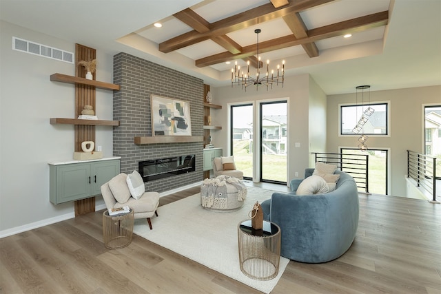 living area with visible vents, wood finished floors, coffered ceiling, and a chandelier