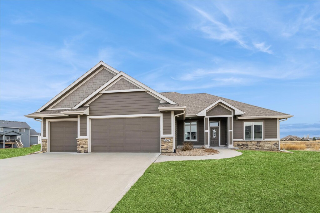 3205 Fieldstone Ct SE, Altoona, IA 50009 - craftsman inspired home featuring a shingled roof, a front lawn, driveway, stone siding, and an attached garage