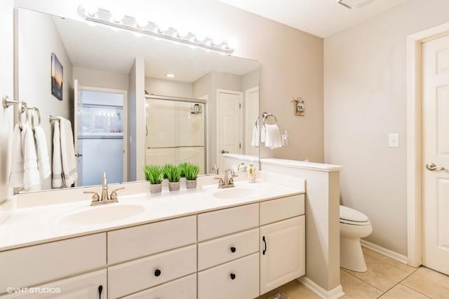 bathroom featuring tile patterned flooring, a shower stall, double vanity, and a sink