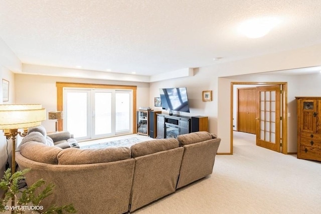 carpeted living area featuring french doors, a textured ceiling, and baseboards