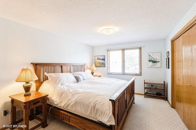 bedroom with light carpet, baseboards, a textured ceiling, and a closet