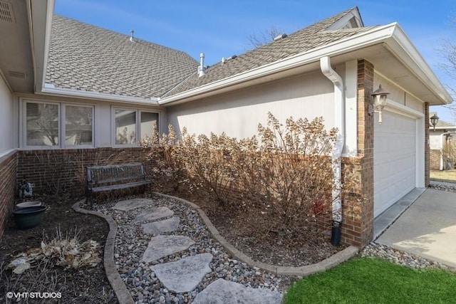 view of side of home featuring brick siding, driveway, a shingled roof, and a garage