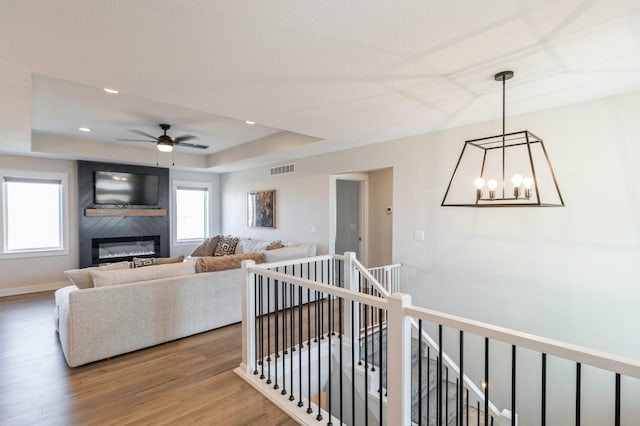 1602 Mulberry St, Granger, IA 50109 - living area featuring a raised ceiling, wood finished floors, ceiling fan, a glass covered fireplace, and recessed lighting