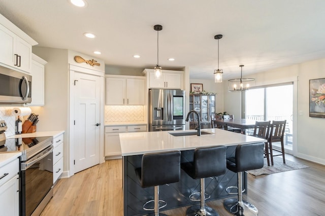 1602 Mulberry St, Granger, IA 50109 - kitchen with stainless steel appliances, a sink, light wood finished floors, tasteful backsplash, and light countertops