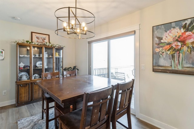 dining space featuring wood finished floors, baseboards, and a chandelier