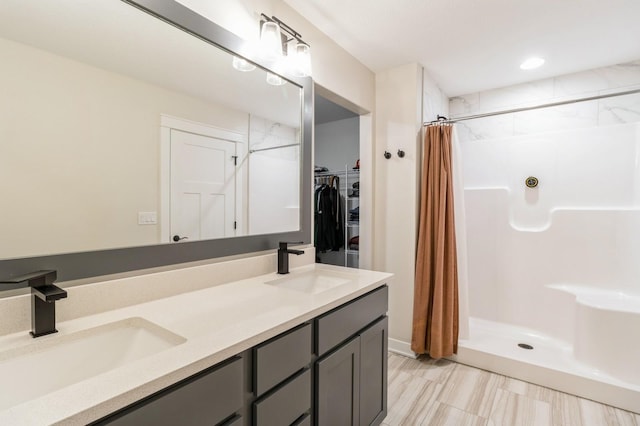 bathroom with a shower stall, double vanity, and a walk in closet