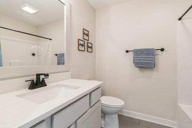 full bathroom featuring toilet, vanity, baseboards, and wood finished floors