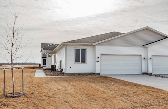 view of front of property featuring central AC, a shingled roof, concrete driveway, a front yard, and an attached garage