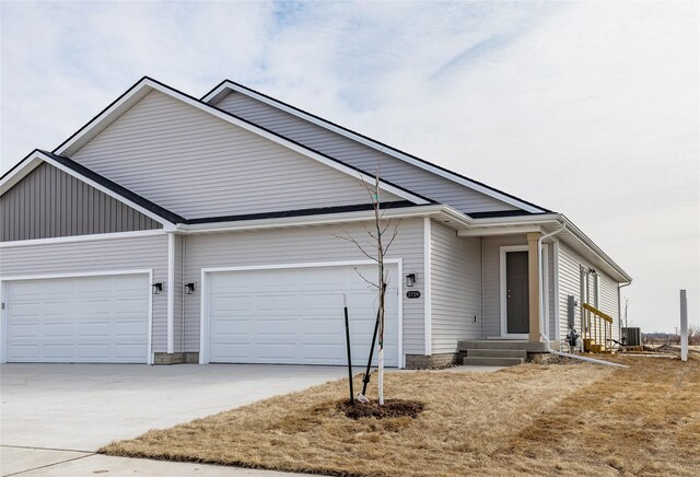 ranch-style house featuring central air condition unit, concrete driveway, an attached garage, and entry steps
