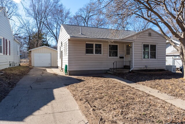 4112 4th St, Des Moines, IA 50313 - view of front facade with driveway, roof with shingles, an outdoor structure, a detached garage, and central air condition unit