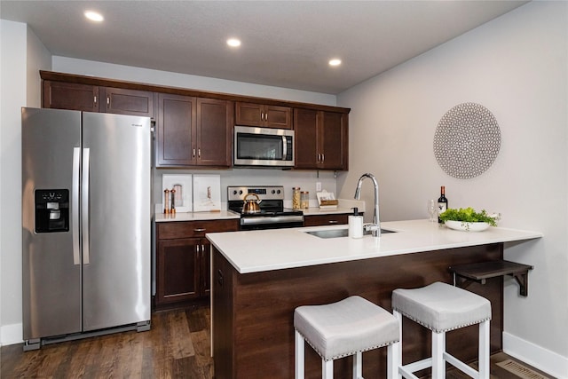 104 Mcpherson St, Boone, IA 50036 - kitchen with stainless steel appliances, dark brown cabinetry, a breakfast bar, and recessed lighting