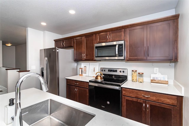 104 Mcpherson St, Boone, IA 50036 - kitchen with appliances with stainless steel finishes, recessed lighting, dark brown cabinets, and a textured ceiling