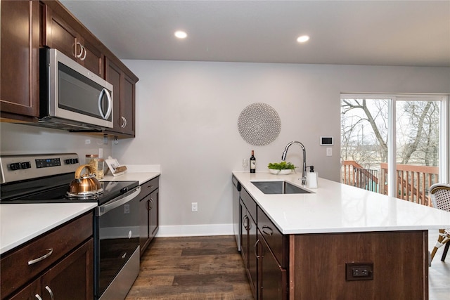 104 Mcpherson St, Boone, IA 50036 - kitchen with appliances with stainless steel finishes, a peninsula, dark wood-style flooring, light countertops, and dark brown cabinets