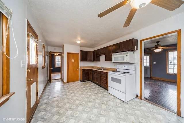 kitchen featuring white appliances, a ceiling fan, light floors, and a sink