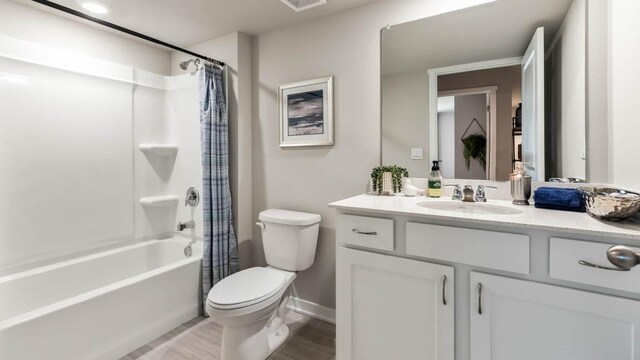 bathroom featuring baseboards, shower / bath combo with shower curtain, toilet, wood finished floors, and vanity