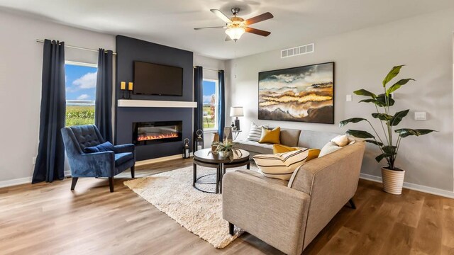 living room featuring visible vents, a large fireplace, baseboards, ceiling fan, and wood finished floors