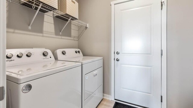 washroom featuring laundry area, washing machine and dryer, and light wood-type flooring