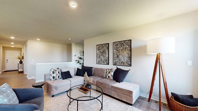 living area with visible vents, a textured ceiling, wood finished floors, recessed lighting, and baseboards