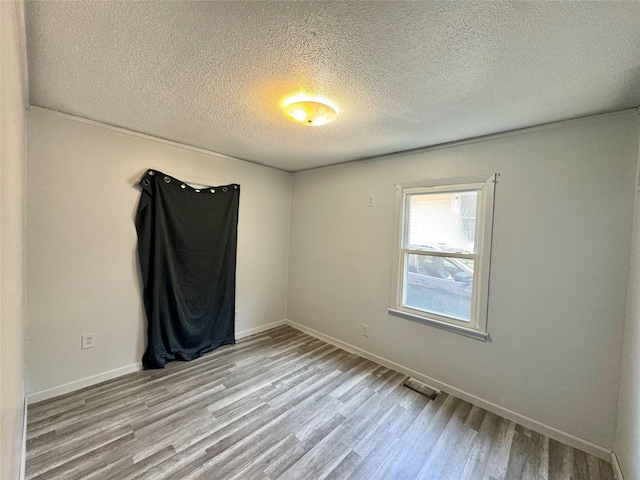 3841 Columbia St, Des Moines, IA 50313 - empty room with a textured ceiling, light wood-style flooring, and baseboards