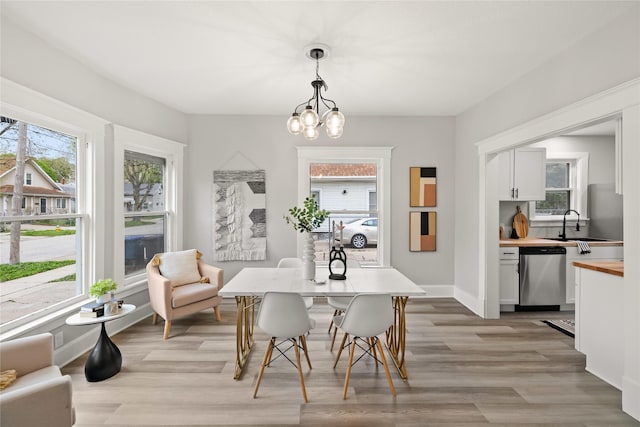 1702 Logan Ave, Des Moines, IA 50316 - dining area with baseboards, a chandelier, and light wood-type flooring